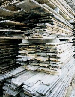 Rough antique lumber is stacked in the yard after initial organizing and tallying.