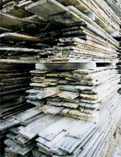 Rough antique lumber is stacked in the yard after initial organizing and tallying.