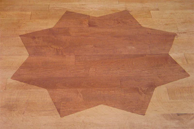 'Popping the grain' drastically darkens the stain color, as shown on this maple floor. The star area was waterpopped, while the rest of the floor was stained without waterpopping.