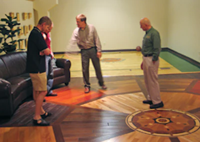Schmidt shows Stoker and Prusow some affordable prefinished flooring options as Lepak, right, looks on.