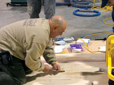 Photo of Manny Navarro using a scraper to fine-tune a sanding job