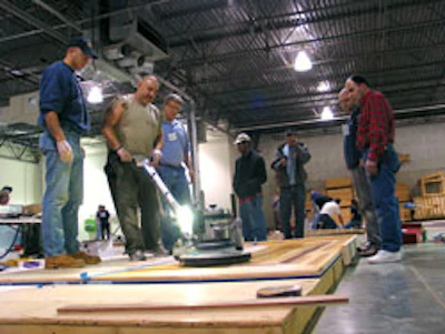 Photo of Manny Navarro using a buffer to apply stain to a floor panel