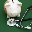 Photo of a stethoscope next to a piggy bank