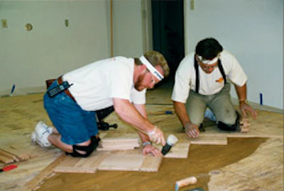 Mel Hollis and Neil Moss help install wood floors at the first National Wood Flooring Association permanent headquarters in August 1997.