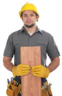 Photo of construction worker holding wooden board