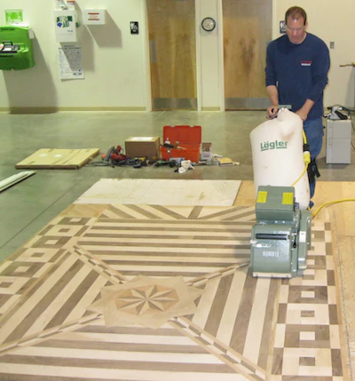 student sanding wood flooring at National Wood Flooring Association (NWFA) technical school