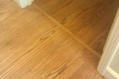 New poly finish on an oak wood floor matches existing finish in a doorway