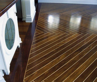 large-format custom herringbone wood floor crafted from exotic afrormosia and hard maple, featuring a santos mahogany border stained to match the mahogany on the windows