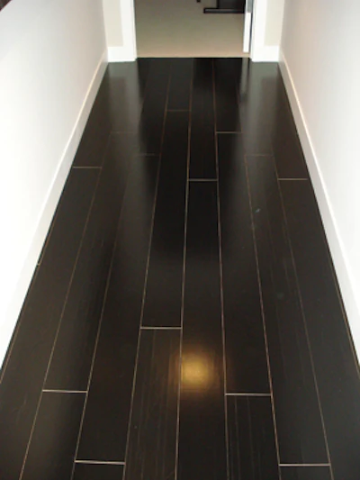 This engineered floor shrank after being exposed to low-humidity conditions, causing it to shrink on all sides and exposing the lighter color of the unstained board edges. Some face-checking is also evident.