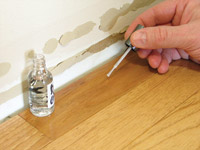 photo of finger nail polish applicator being used on wood floor