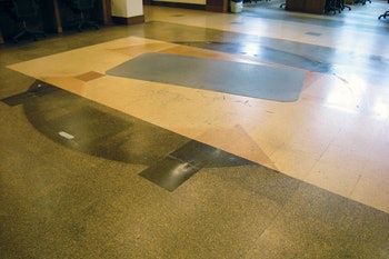 (BEFORE) In this before photo, you can see a circular center area where there was a reception desk; the brown tiles had faded to a grayish color, but some didn't fade quite as much because they were covered by the desk.