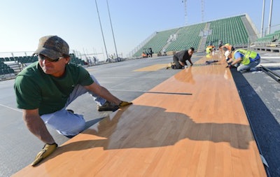 Workers install a basketball court on-board the USS Bataan for the matchup between Georgetown and Florida. (Photo credit: Mass Communication Specialist Seaman Rob Aylward)