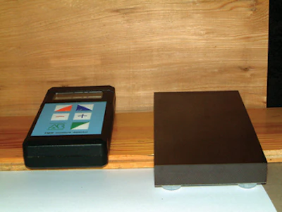 This pinless meter is shown with a calibration block that verifies the meter is working correctly on the right. The preferred direction with this moisture meter model is across the grain.