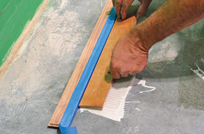 photo of someone gluing down flooring to backer a board