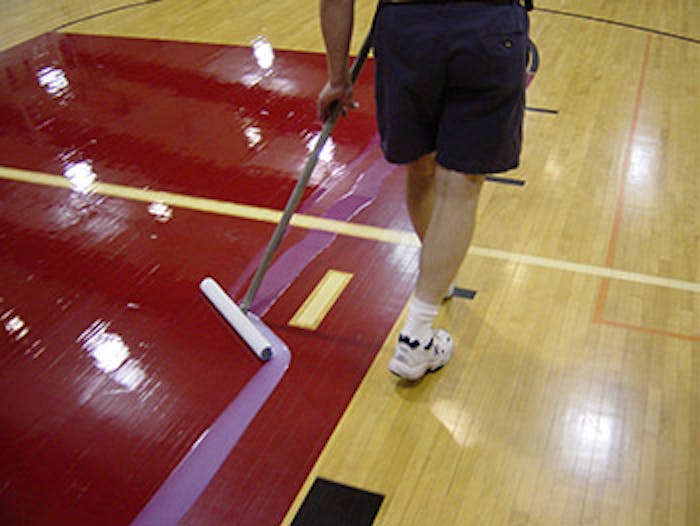photo of someone finishing an athletic wood floor