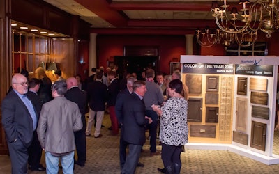 Attendees at the AkzoNobel client appreciation gala mingle in front of an exhibit displaying Ochre Gold, the color of the year.