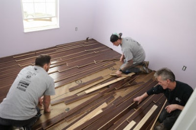 Volunteers organized by Lockwood Flooring install Sheoga hardwood flooring in a bedroom at Army veteran Chris Sanna’s home.