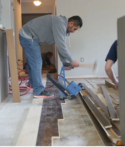 Volunteer installing Sheoga hardwood flooring in the living room at Army veteran Chris Sanna’s home.