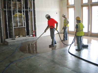 These contractors are using a grout pump to spread the self-leveler.