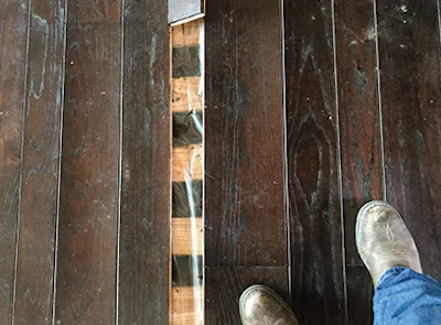 This is a typical plank floor over screeds with plastic on top of the screeds; in this area it's common to use plastic over screeds to protect the wood from nuisance leaks like those from an icemaker. In situations like this, though, that works against us, because the plastic acts like a glass ceiling. Although we can save many cupped floors, for a buckled floor like this it doesn't make sense to try to save the floor.
