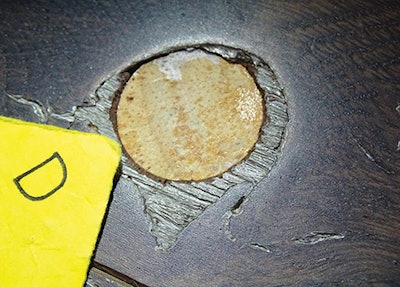 Underneath lighter-looking areas of filler, these round poker-chip-like wood pieces were embedded in the prefinished wood flooring.