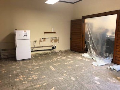 The historic wood floor pictured peeking through the glue after the vinyl floor that had hidden it was removed.
