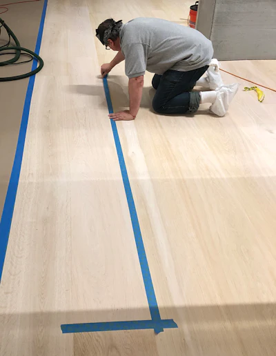 The client wanted a uniform look to the floor, but the boards had been racked out randomly, so our first priority was to tape off individual boards as necessary to even out the color differences.