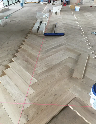 In this area we installed the big block engineered herringbone directly over the old chevron. We ran multiple string lines, and it was critical where we started and stopped, as the blocks were a custom width and length to eliminate any half blocks; the entire floor was symmetrical. Below, the herringbone during sanding. Bottom, after we applied PreTone.