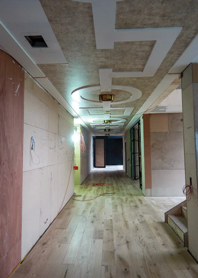 The long, straight passage was more than 20 meters (about 66 feet) long and was the reason we had to air-freight in long boards mid-installation. The wood floor in this area was left plain so that the ceiling was the feature. Middle photo, the passage after the walls were installed and finished but before we buffed and burnished the floor. When the home was complete, a custom rug mirroring the ceiling was placed over the floor.