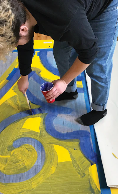 Above, artist Johnathon Alejandro Arce from Carlos Rolón's studio helps implement Rolón's vision on the floor.