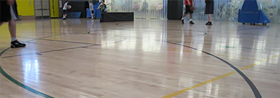 Photo of a basketball court showing definite damage by excess moisture. After analyzing the problem, it was found, that the outside walls of the building were not insulated properly. Whenever it rained, moisture would migrate through the walls and increase the relative humidity in the gymnasium and enable the floor planks to absorb more and more moisture.