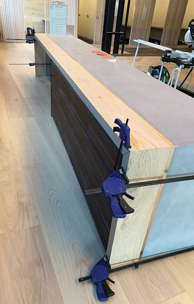 The main part of the counter was created by a concrete company. Here, I've glued and clamped the pieces I created in my shed to the concrete in the showroom.