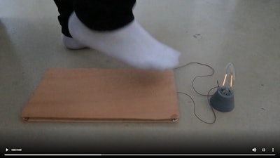 A still from a video demonstrating how the flooring can power a household lamp.