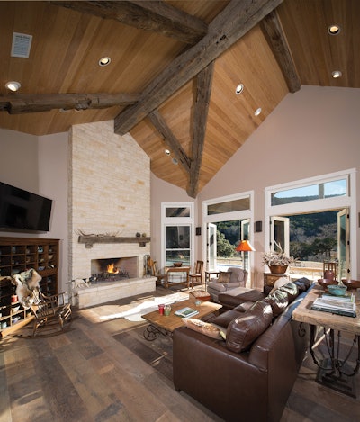 The family room features a ceiling made of cypress paneling and vaulted timber beams reclaimed from centuries-old structures. The floor is wide-plank reclaimed white oak.
