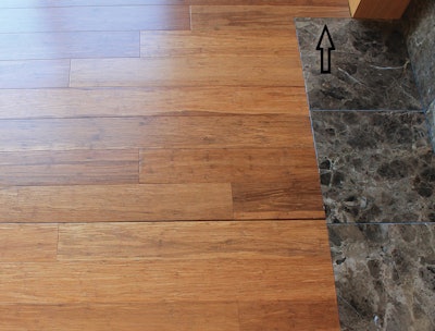 This floating click strand bamboo floor is beginning to show a large gap due to being installed tight against the hearth without any expansion space in the spot indicated with the arrow.