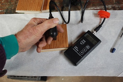 The flooring wear layer (top) and plywood core (bottom) were tested for moisture content using an invasive pin meter.