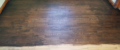 “On this floor the customer first used a Square Buff in the field (all the grits, one after the other, on one day). Then, on a separate day, he used a belt sander to sand what the Square Buff missed, but because he didn’t alternate with the machine that did the field, each “edge” pass came out a little further than the last one. By the time he was done, he was halfway into the floor. And he clearly was leaning hard on that belt sander, because it left more porosity in the wood, and his stain penetrated more deeply on that edge. Best picture frame eva!”