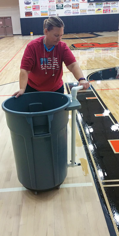We call this contraption (above) the “Zehnder finish barrel” because Rob Zehnder was the one who originally showed us the idea—it’s a trash can with a valve at the bottom that allows the finish to meter out. In our area, here in the high desert, our struggle is extremely low humidity—so much that if you pour a ribbon of finish the length of a gym, the finish can start to dry out on the floor before you spread it. With this, we can put our gallons of waterborne finish in, add the recommended amount of water to extend dry times, add our hardener and mix it all easily. Using this, I can actually coat a gym floor by myself.