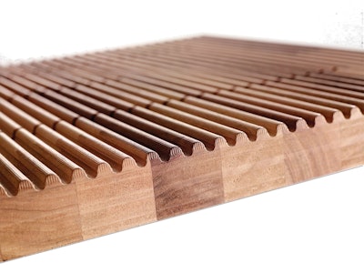 The designer used American walnut slabs and a CNC cutter to create grooves in the surface. The floor makes sound when objects are rolled over it (opposite).