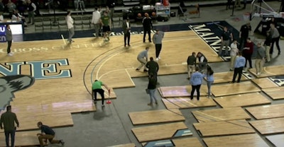 Arena staff reassemble the court after the baseline was discovered to be crooked prior to tipoff.