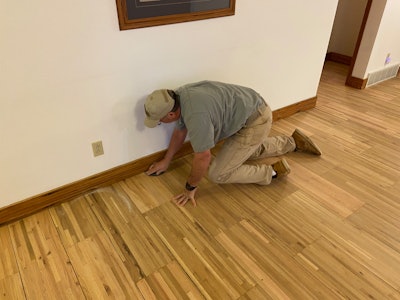 It’s important to make sure the edges are abraded just as well as the field. Here, Scott Bowman of Bowman’s Hardwood Floor Refinishing abrades the edges on a floor made of cutoffs from trailer flooring.