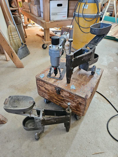 The box pictured here did dual duty as a tool box to hold everything you needed for your Cavanaugh nailer, plus it was a rolling seat you used while nailing with the Cavanaugh all day. At the top right and on the floor are original Cavanaugh nailers, and on the top left is the modern version of the Cavanaugh we use today, the HighPro HP-50.