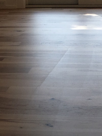 This waterborne finish didn’t fail, but with nearly floor-to-ceiling windows in the home, the contractor’s cross-board application shows up in the finish (even with a super-low sheen). Always coat the floor “with the flow of the boards” when possible.