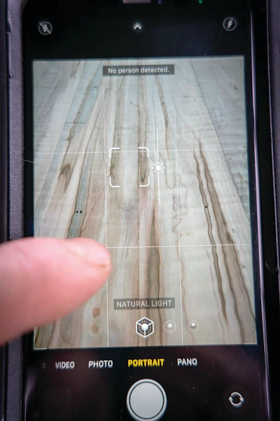 While in camera mode, tap the screen where you want the focus of your image to be, you should see a square and sun with lines. This will give you control over focal point, as well as the lighting exposure of your image. With a gentle up or down slide from your finger tip, you can make your photo lighter or darker. Also, most smartphone camera apps have a portrait mode. This mode can give you a little more automatic lighting control if need be.