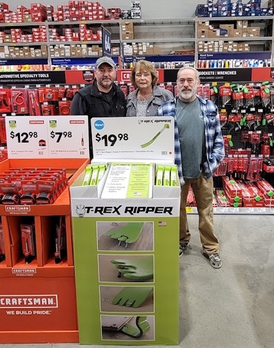 Jerry Sindt (left), Jason Sindt (right), and Marilou Warren (center), partner Ron Warren's widow, standing at a T-Rex Ripper display at Lowe's.