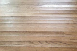 Using the wrong products can allow excess moisture to affect the wood flooring—cupping (shown here) is just one potential problem.