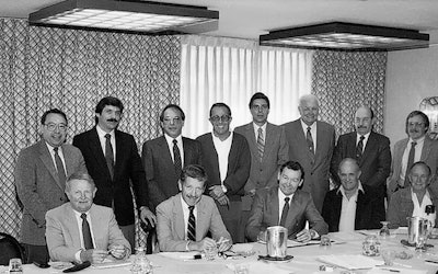 At this meeting in St. Louis in December 1985, the National Wood Flooring Association was officially created. Seen are (seated, left to right): Jack Wilcox, H.G. Roane Company; Ralph Singer, Diamond W Supply; Lon Musolf, Lon Musolf Distributing; Roland Holder, Gentry & Holder Floors; Harold Reid, Trinity Floor Company; (standing, left to right): Gary Reynolds, Galleher Hardwoods; Steve Brown, Swift-Brown Distributors; Art Pedicini, Geysir Sales Corporation; Jack Coates, Golden State Flooring; Richard Steeneck, Hoboken Wood Floors; Virgil Hendricks, Mid-West Floor Company; Eldon Robbins, Mid-West Floor Company; and Keijo Hyvonen, Kelly-Goodwin Company.