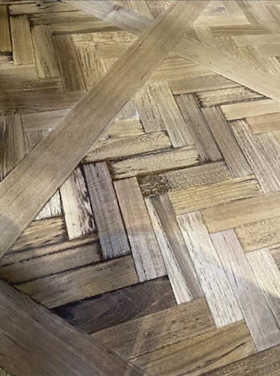 Many factors can contribute to bleedback—when stain keeps seeping back up to the surface of a wood floor. In this case, too much stain was applied and pooled below the herringbone slats.