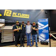 P.C. Floors team members posing in showroom with floor samples and Chamber of Commerce banner
