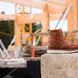 Leather work boot on stone at construction site with wooden framing